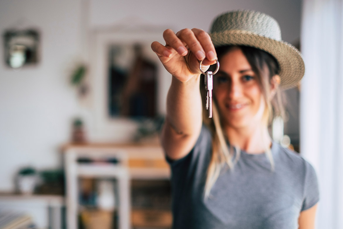 woman holding out house keys, buying your first home